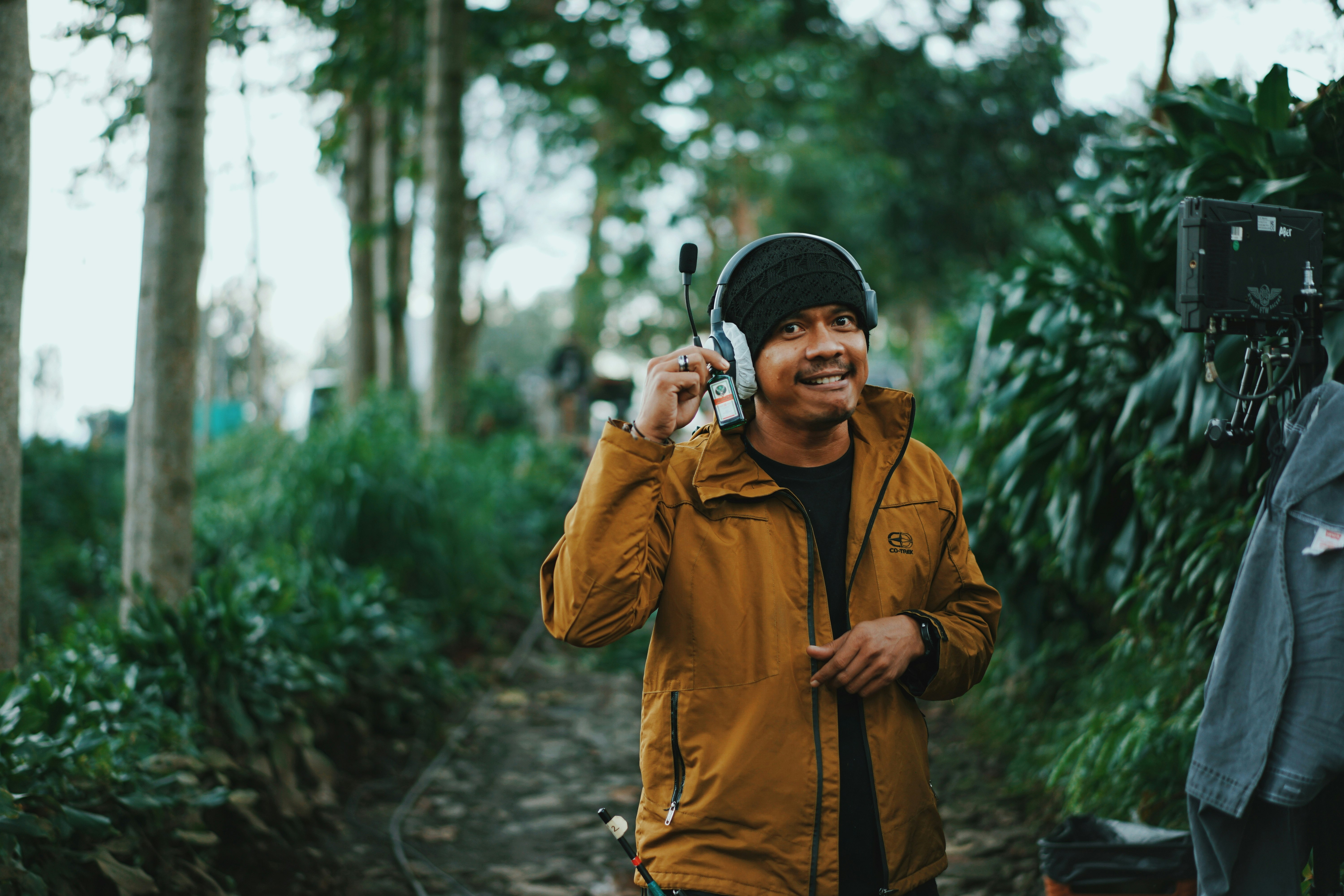 man in brown jacket holding smartphone